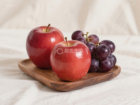 红苹果与葡萄置于木质盘中