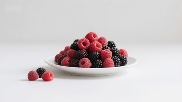 新鲜浆果堆放在白色盘子上