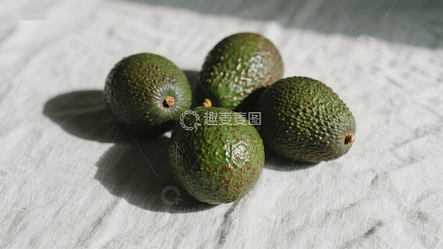 四个牛油果静置于白色布料上