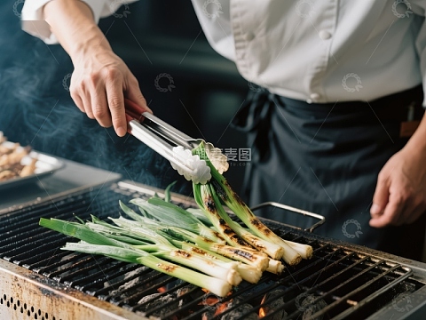 厨师用夹子翻转烤架上的葱