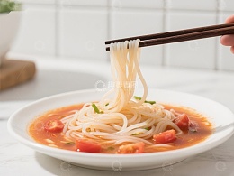 筷子夹起面条，碗中番茄汤面诱人