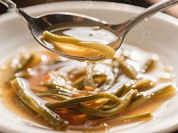 热汤中的豆角，勺子舀起特写