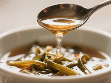 勺子舀起热汤，汤中蔬菜清晰可见