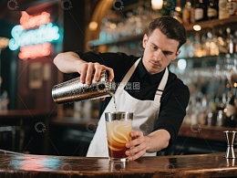 调酒师倾倒鸡尾酒入杯