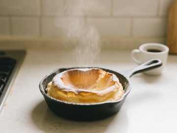 糖粉撒在煎锅中的荷兰松饼上