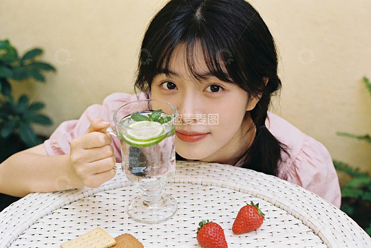 女子手持饮品与草莓静坐