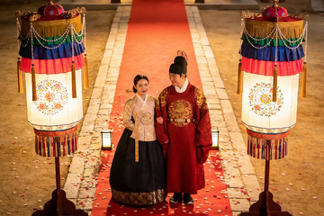 身着传统服饰的新人在红毯上合影