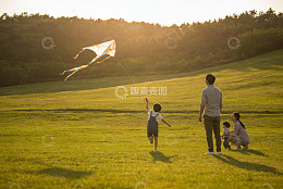 夕阳下草地放风筝的温馨家庭