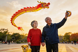 老年夫妇放龙风筝遛狗