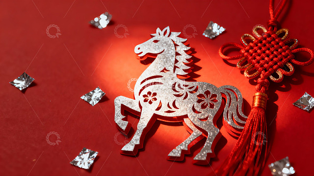 红色背景上的银色马形剪纸与中国结