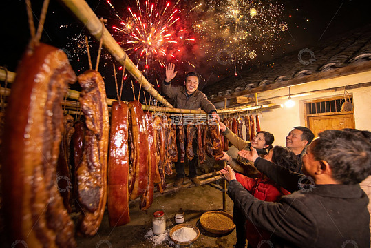 烟花下家人挂腊肉庆祝节日